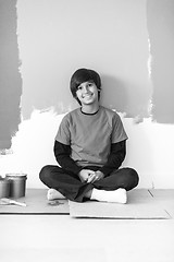 Image showing young boy painter resting after painting the wall