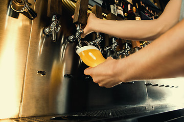 Image showing Hand of bartender pouring a large lager beer in tap.