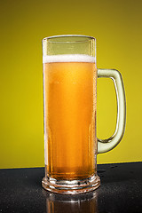 Image showing glass of cold frothy lager beer on an old wooden table