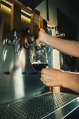 Image showing Hand of bartender pouring a large lager beer in tap.