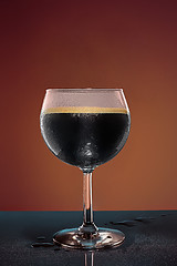 Image showing glass of cold frothy dark beer on an old wooden table