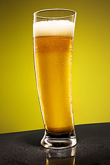 Image showing glass of cold frothy lager beer on an old wooden table