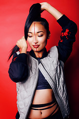 Image showing young pretty asian girl posing cheerful on red background, fashion style makeup and hair, lifestyle modern orient people concept