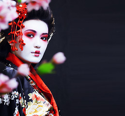 Image showing young pretty geisha in kimono with sakura and decoration