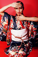 Image showing young pretty geisha on red background posing in kimono, oriental people concept close up