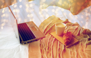 Image showing laptop, coffee and croissant on bed at cozy home