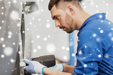 Image showing auto mechanic with screwdriver changing car tire