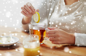 Image showing close up of woman adding honey to tea with lemon