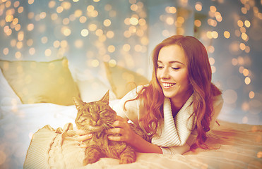 Image showing happy young woman with cat lying in bed at home