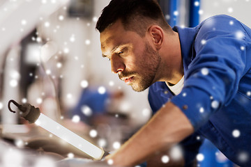 Image showing mechanic man with lamp repairing car at workshop