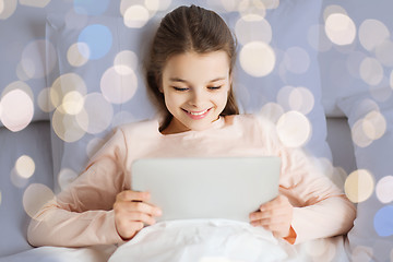 Image showing happy girl in bed with tablet pc over lights