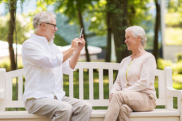 Image showing old woman photographing man by smartphone in park