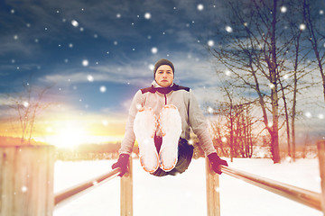 Image showing young man exercising on parallel bars in winter