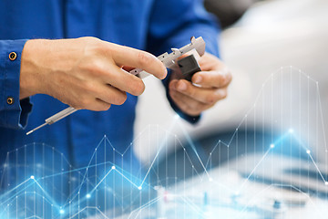 Image showing mechanic with calipers measures detail at workshop