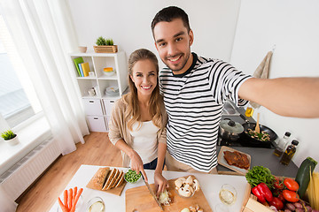 Image showing couple cooking food and taking selfie at kitchen