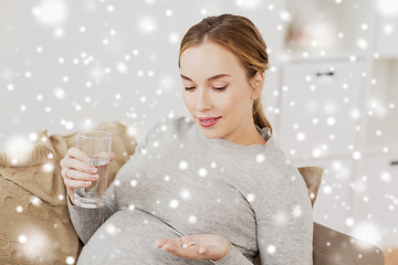 Image showing happy pregnant woman with water and pills at home