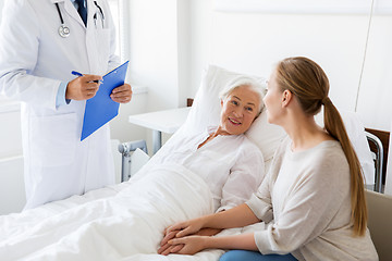 Image showing senior woman and doctor with clipboard at hospital