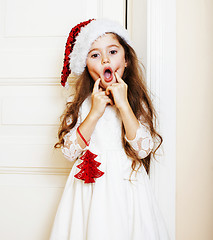 Image showing little cute girl in santas red hat waiting for Christmas gifts. 