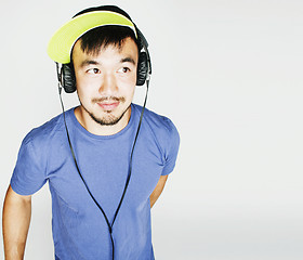 Image showing young asian man in hat and headphones listening music on white b