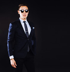 Image showing young pretty business man standing on black background, modern h