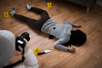 Image showing criminalist photographing dead body at crime scene