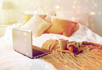 Image showing laptop, coffee and croissant on bed at cozy home