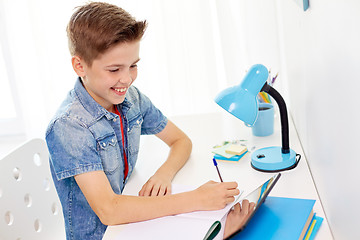 Image showing student boy with tablet pc writing to notebook