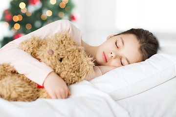 Image showing girl sleeping with teddy bear in bed at christmas