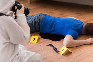 Image showing criminalist photographing dead body at crime scene