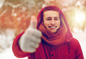 Image showing happy man in winter jacket showing thumbs up