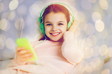 Image showing girl with headphones listening to music in bed