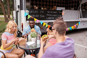 Image showing happy friends with drinks eating at food truck