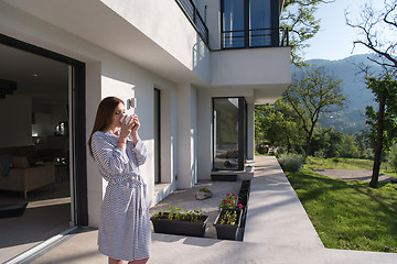 Image showing woman in a bathrobe enjoying morning coffee