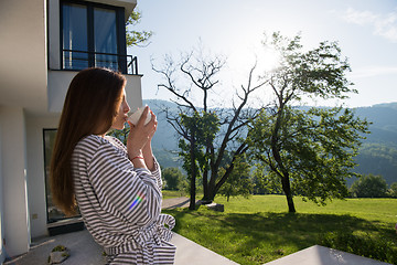 Image showing woman in a bathrobe enjoying morning coffee