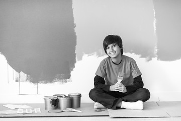 Image showing young boy painter resting after painting the wall