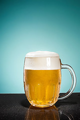 Image showing glass of cold frothy lager beer on an old wooden table