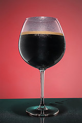 Image showing glass of cold frothy dark beer on an old wooden table