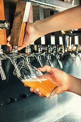 Image showing Hand of bartender pouring a large lager beer in tap.