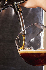 Image showing Hand of bartender pouring a large lager beer in tap.