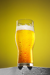 Image showing glass of cold frothy lager beer on an old wooden table