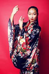 Image showing young pretty geisha on red background posing in kimono, oriental people concept close up