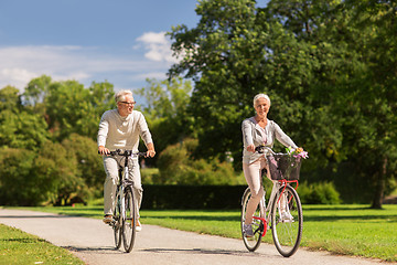 Image showing happy senior couple riding bicycles at summer park