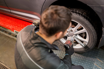 Image showing auto mechanic with screwdriver changing car tire