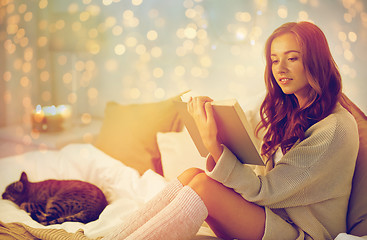 Image showing happy young woman reading book in bed at home