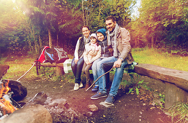 Image showing happy family sitting on bench at camp fire