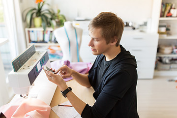 Image showing fashion designer with smartphone working at studio