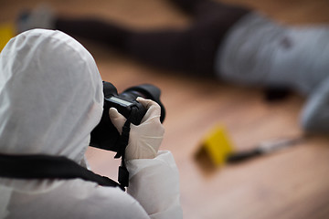 Image showing criminalist photographing dead body at crime scene