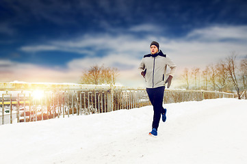 Image showing man running along snow covered winter bridge road