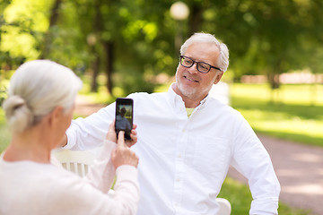 Image showing old woman photographing man by smartphone in park