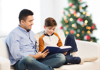 Image showing happy father and son reading book at christmas